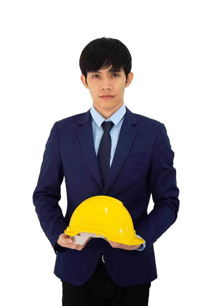 Un homme d'affaires asiatique debout avec un casque jaune à la main et isolé sur fond blanc photo