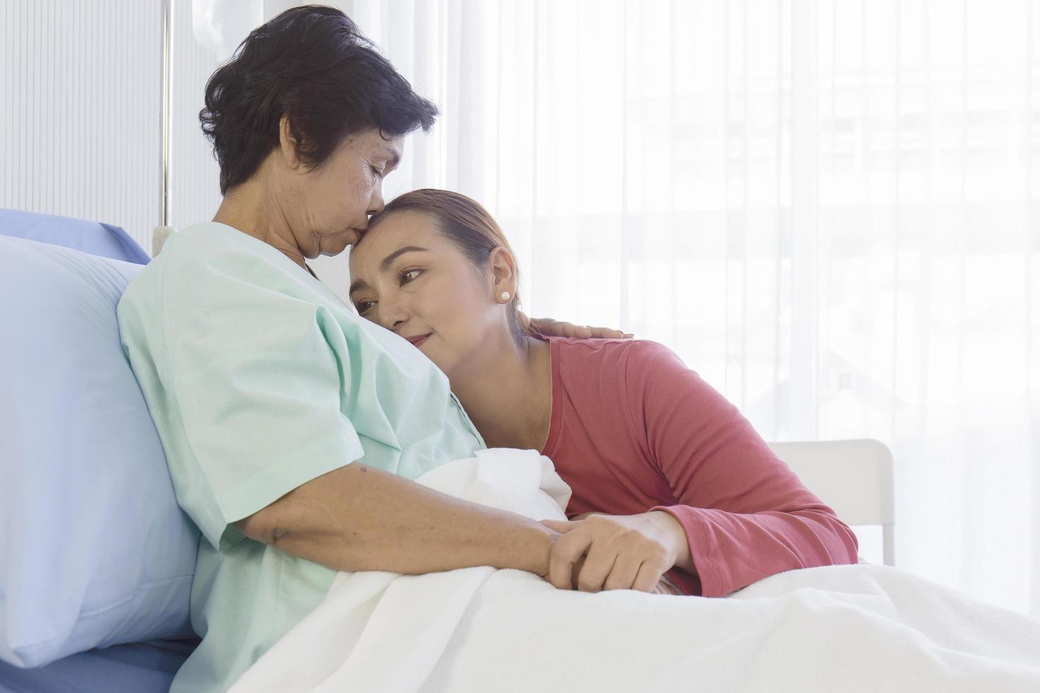 une fille asiatique prend soin de sa mère malade sur un lit dans un hôpital. photo