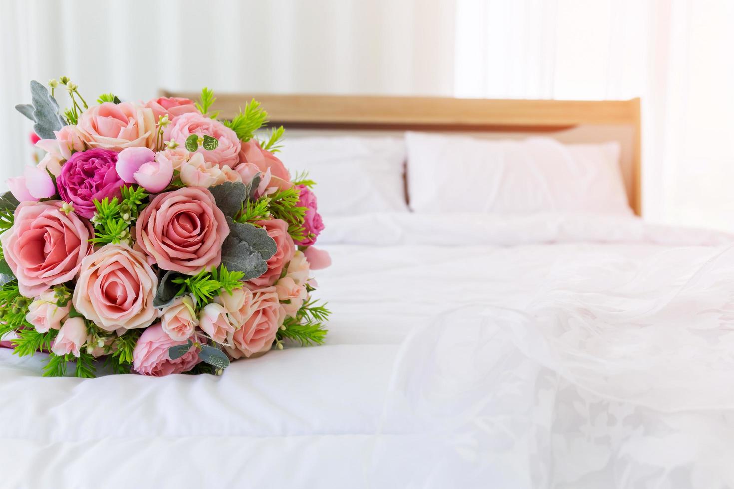 un beau bouquet de fleurs était disposé sur un lit propre et blanc. à côté de la robe de mariée ont été placés ensemble. photo