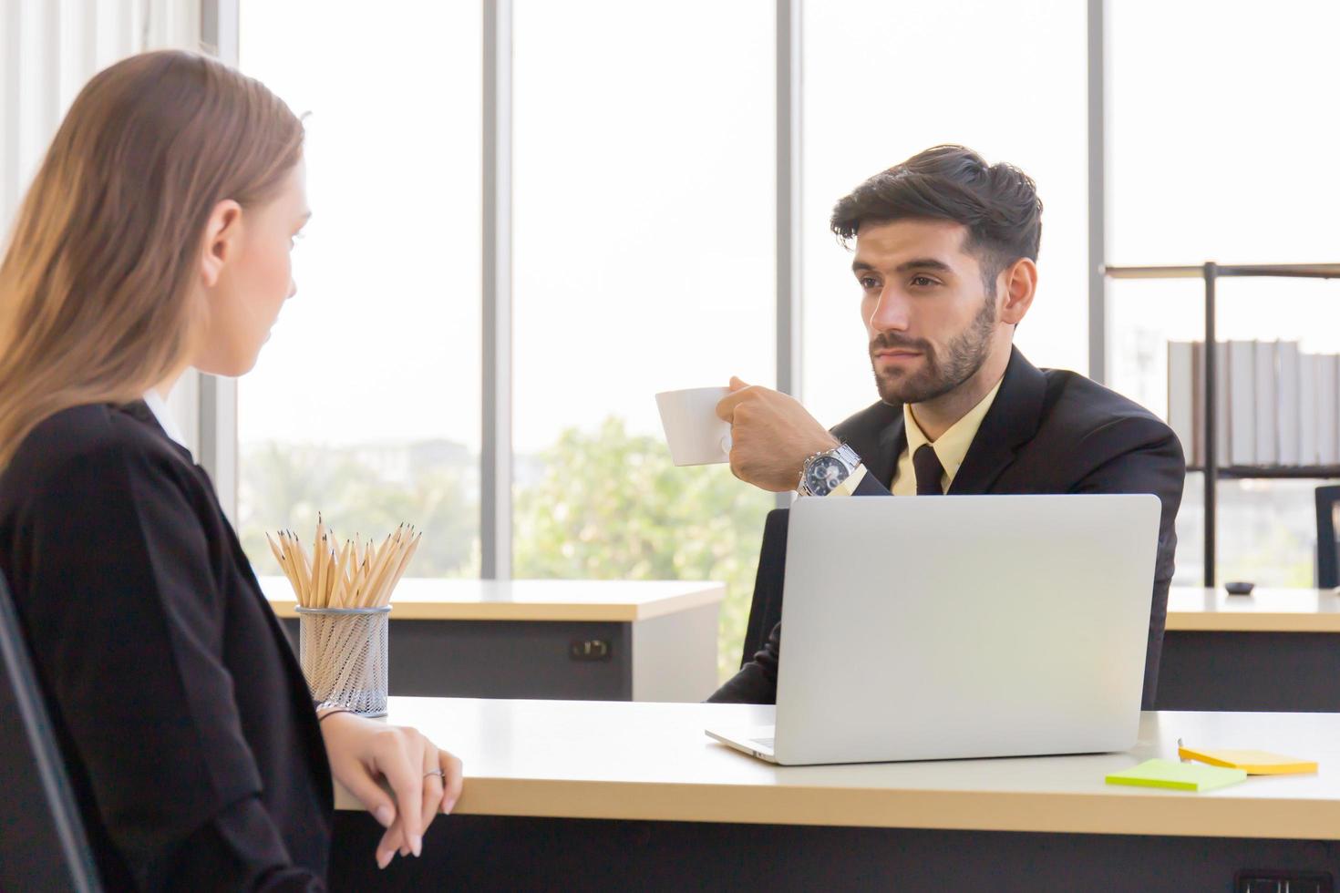 un homme d'affaires masculin tient une tasse de café avec la secrétaire féminine au bureau d'une manière sérieuse photo