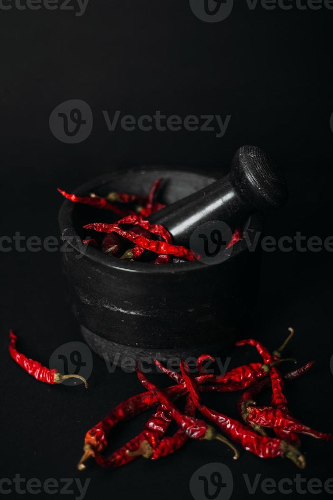 poivrons épicés rouges secs et poudre sur fond noir photo