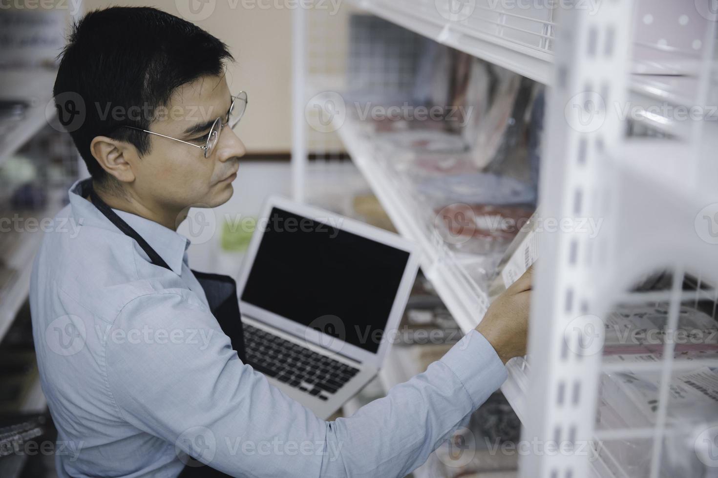 homme d'affaires propriétaire personnel utilisant un ordinateur portable vérifiant l'étagère de l'inventaire des produits dans l'épicerie photo