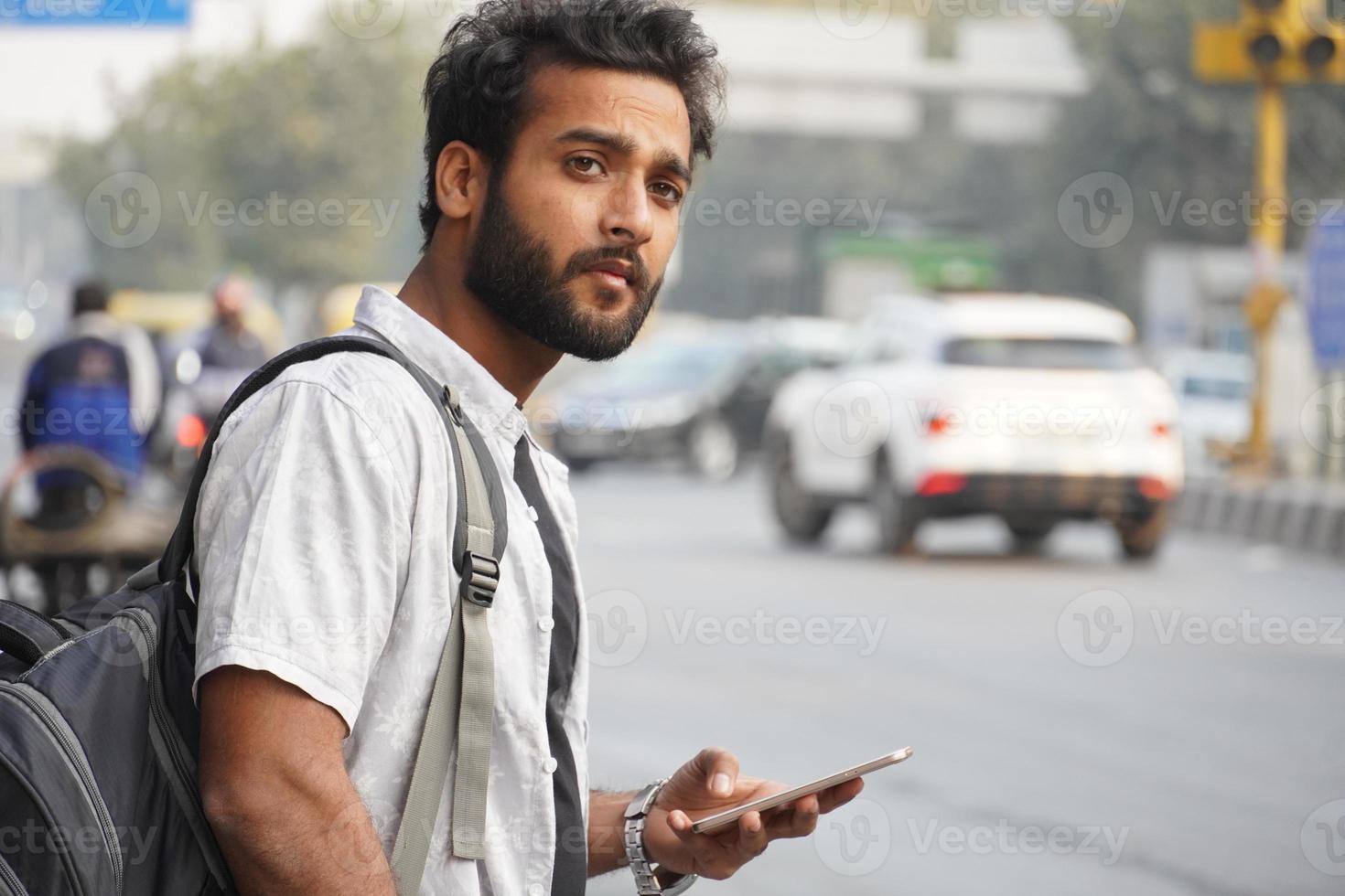 un homme attendant une voiture ou un bus et utilisant un téléphone portable photo