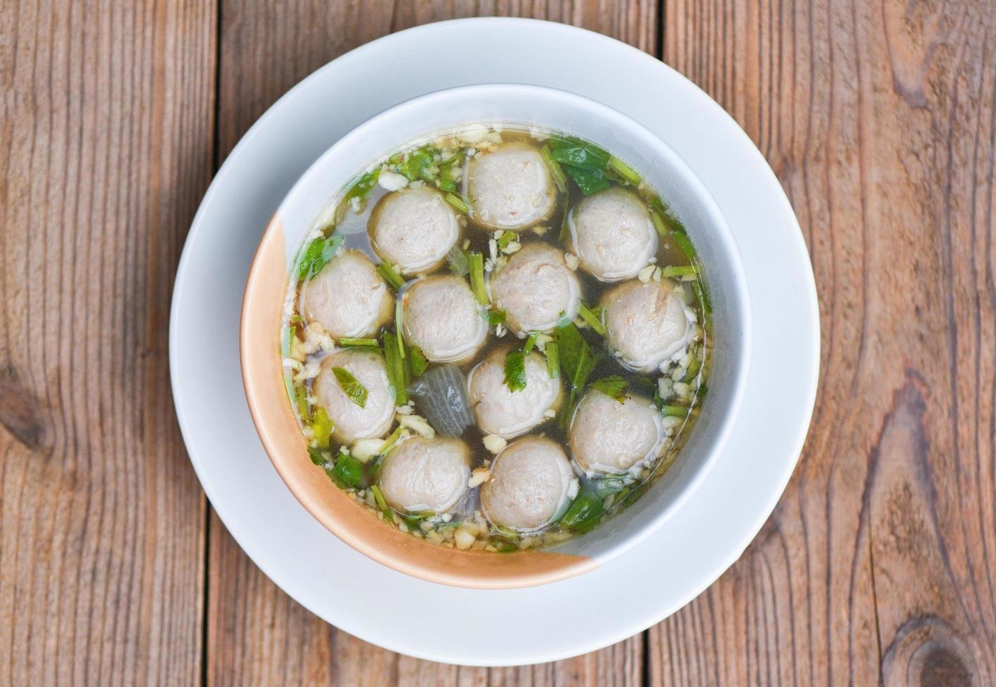 bol de soupe aux boulettes de viande, boulette de viande thaïlandaise asiatique et boulettes de porc sur fond de bois photo