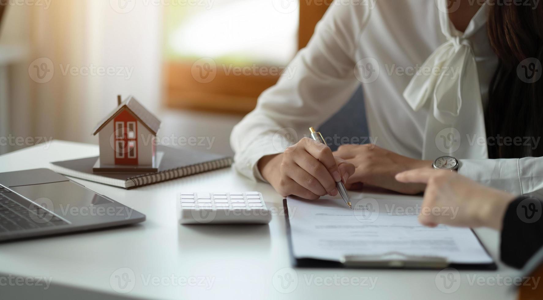 modèle de maison avec agent et client discutant d'un contrat d'achat, d'assurance ou de prêt d'un bien immobilier ou d'une propriété. photo
