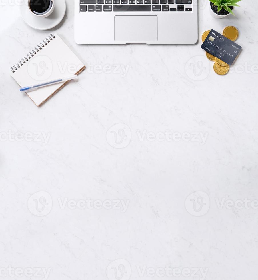 concept de conception financière d'entreprise, vue de dessus de table de bureau en marbre blanc avec téléphone intelligent, carte de crédit maquette, pièces de monnaie, ordinateur portable, pose à plat, espace de copie photo