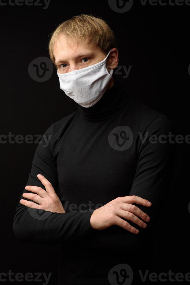 un homme d'âge moyen avec un portrait de masque médical en gros plan illustre une pandémie de coronavirus sur fond sombre. concept de contamination de l'épidémie de covid-19. photo