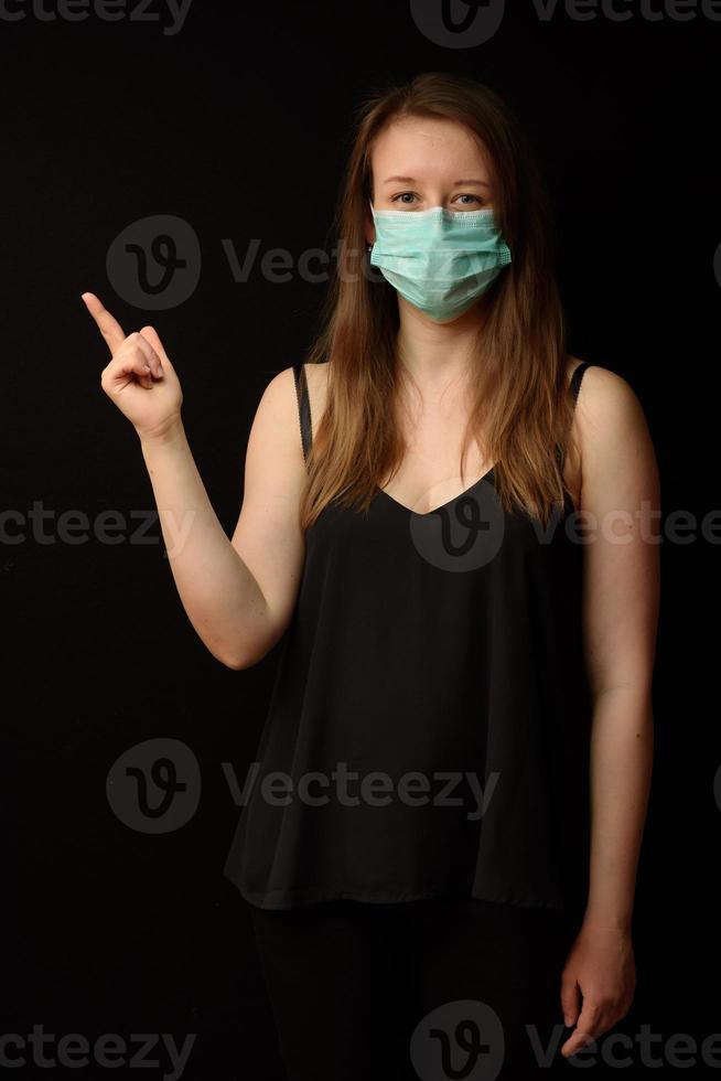 fille en masque médical pointe un doigt vers votre produit, texte. photo