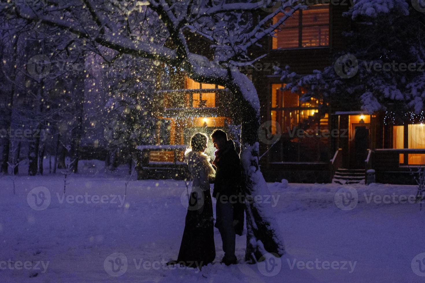 belle mariée et le marié avec un chien blanc se tiennent sur le fond d'une forêt enneigée. photo