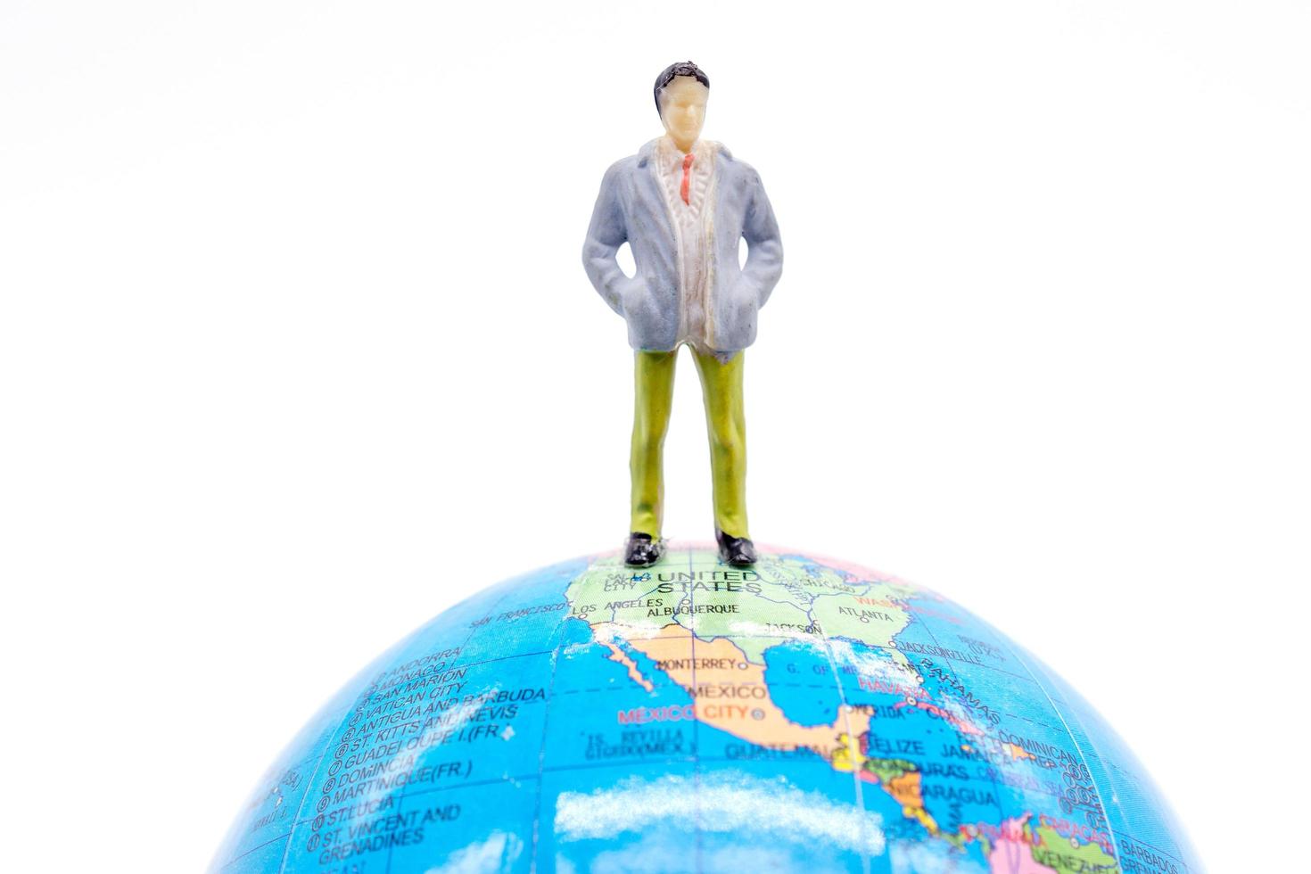 Homme d'affaires miniature sur le globe sur fond blanc photo