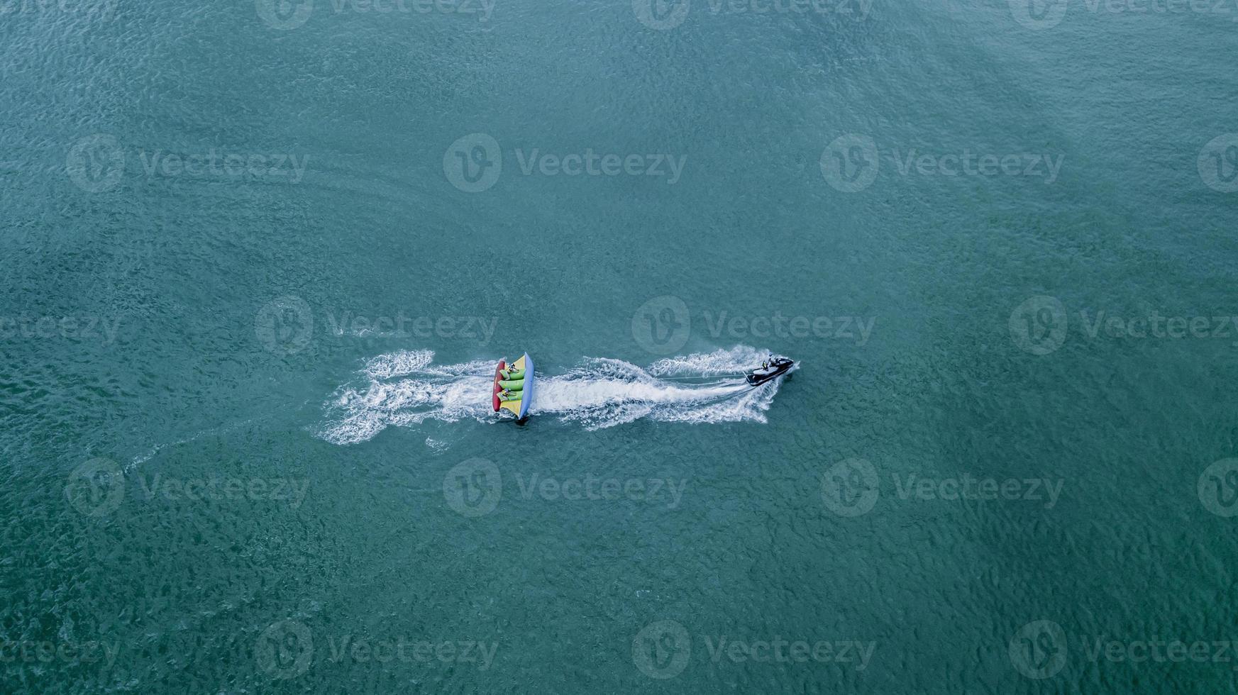 bateau banane gonflable avec des touristes en mer calme bleue. groupe de personnes faisant du bateau banane. s'enfuyant à grande vitesse. photo