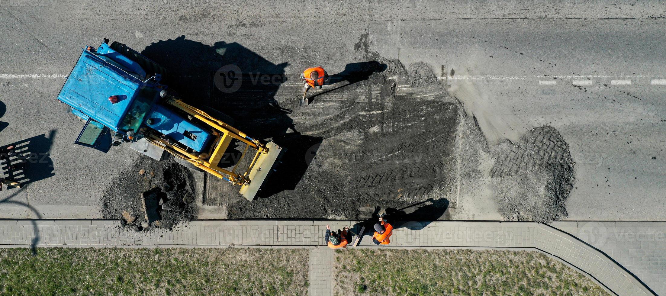 vue aérienne des travailleurs de la route réparent le revêtement d'asphalte. notion de travail d'équipe. contraste entre le nouveau et l'ancien revêtement routier. photo