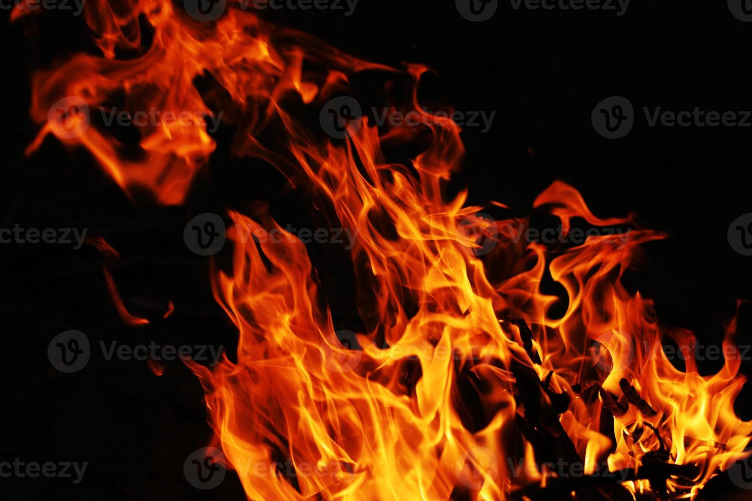 le feu crée des formes infinies lorsqu'il brûle. l'orange de la flamme et le fond noir créent des textures intéressantes. flammes de l'enfer. puissance brûlante. photo
