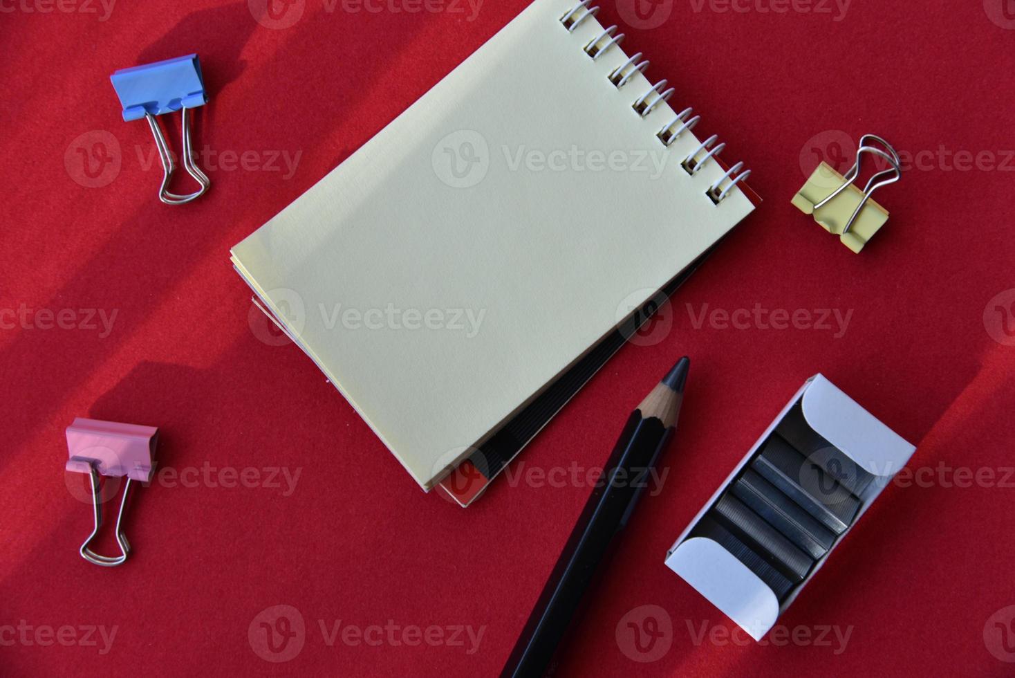 Perforatrice de crayons et bloc-notes sur fond rouge photo