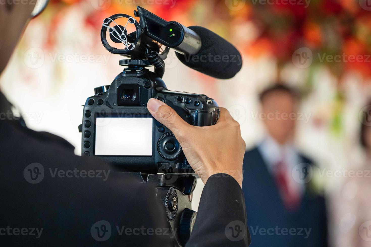 une vidéaste à l'arrière filme et enregistre une vidéo lors d'un événement de mariage. photo