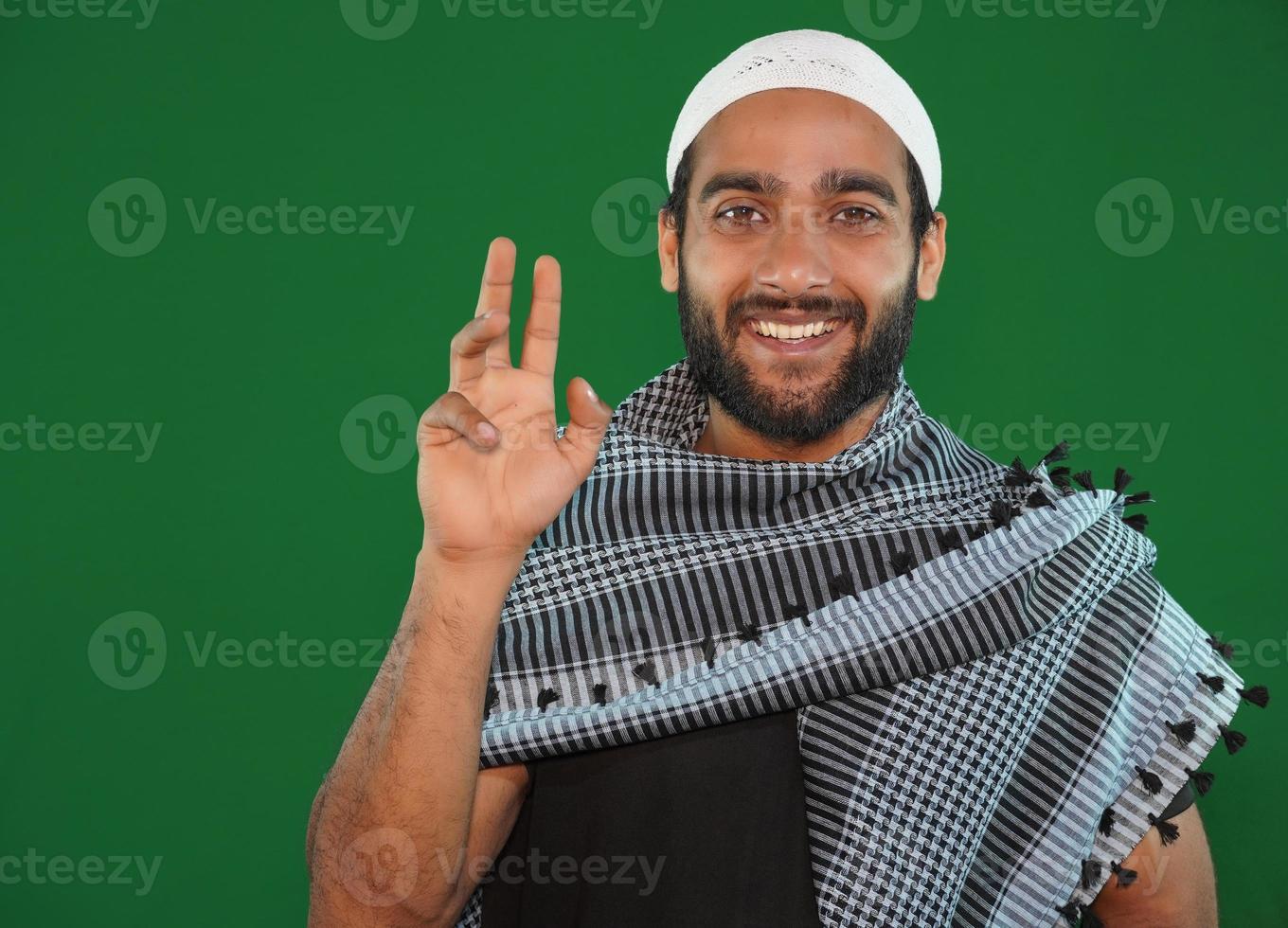 garçon musulman disant bonjour sur fond d'écran vert. photo