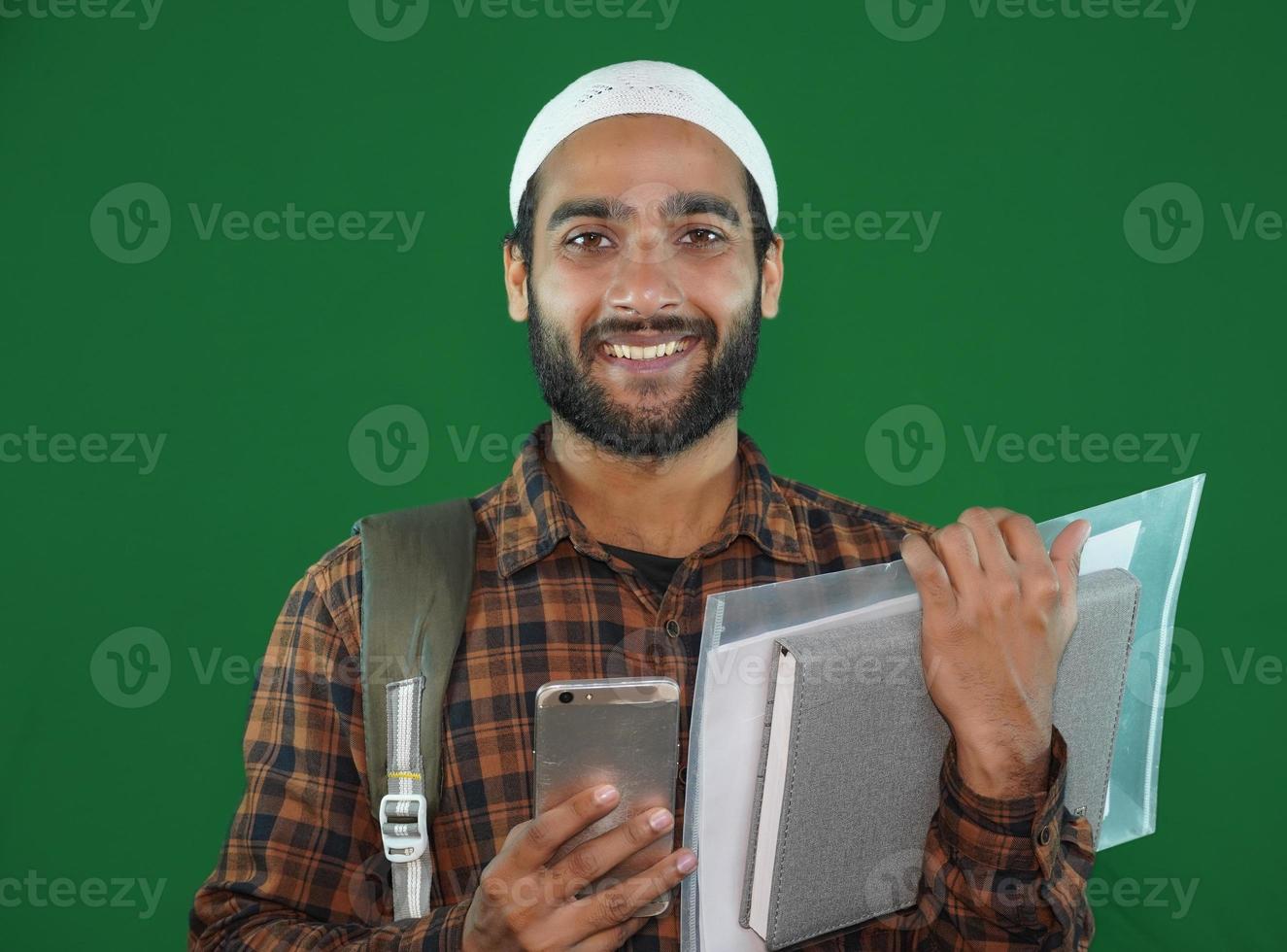 jeune étudiant garçon musulman avec des livres sur fond d'écran vert. photo