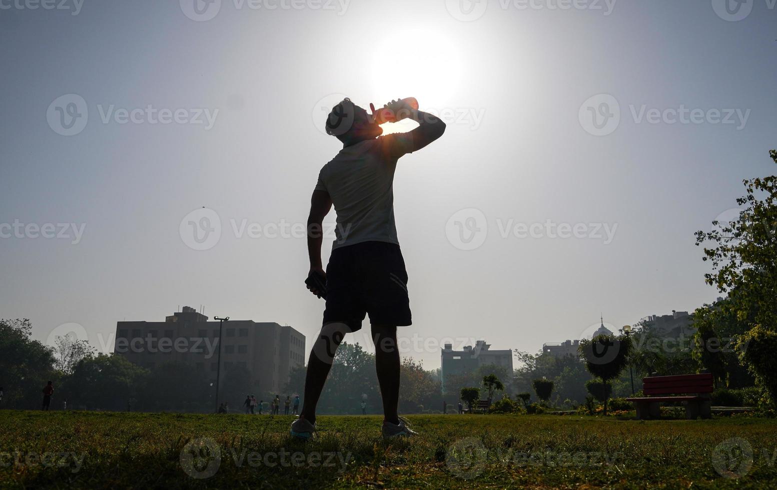 Homme au stedium sur l'image de la silhouette avec une bouteille de shaker pour la salle de sport et boire gainer -concept de forme physique photo