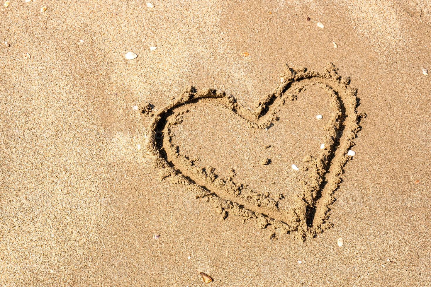 un dessin d'un coeur sur un sable jaune sur un beau fond de paysage marin. composition horizontale. photo