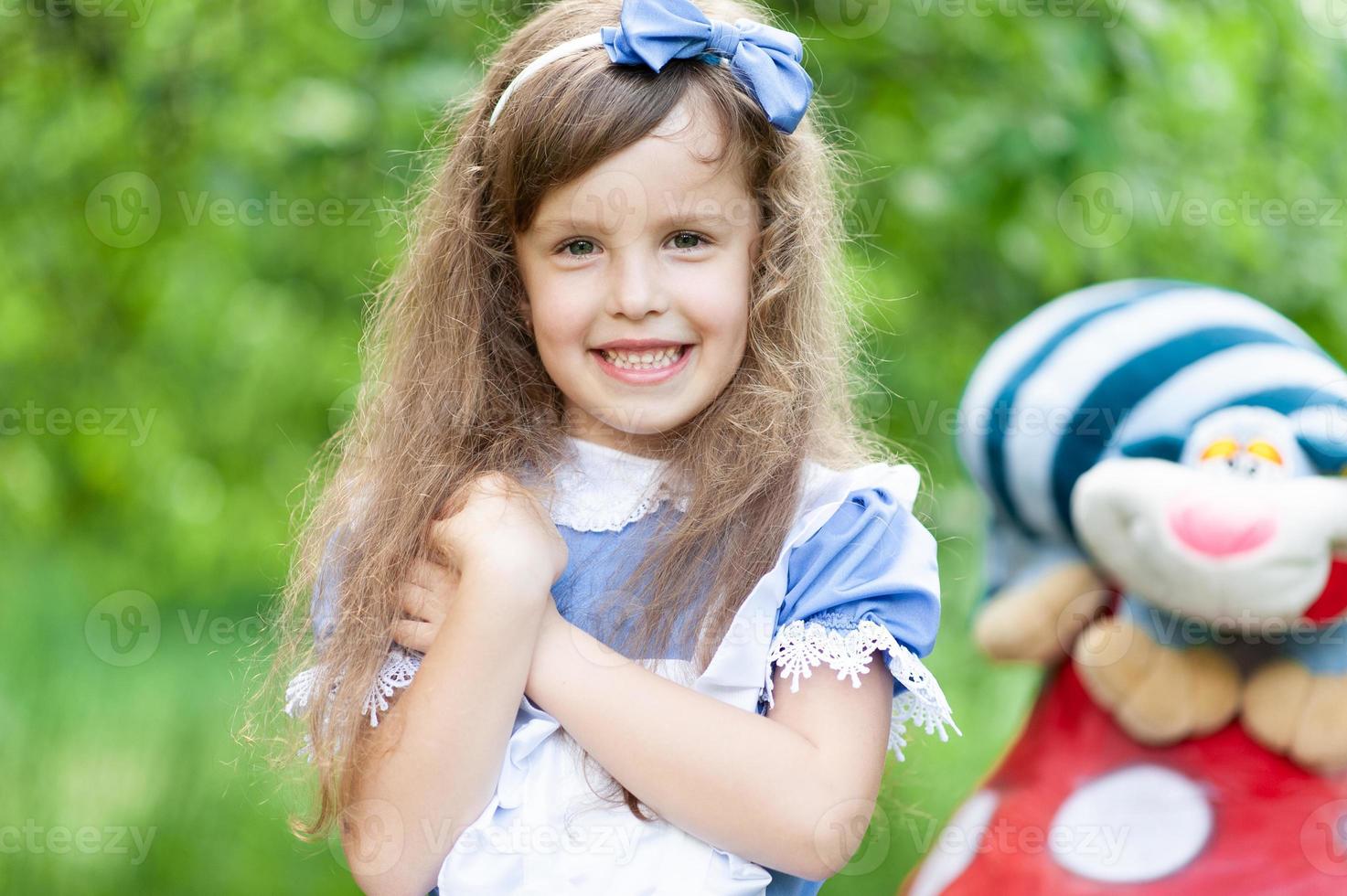 portrait d'une petite fille mignonne habillée en alice. séance photo stylisée dans la nature.