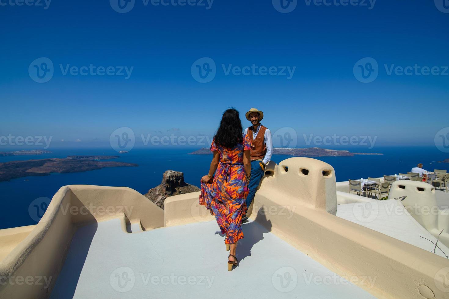 un homme et une femme se serrent dans leurs bras sur fond de rocher de skaros sur l'île de santorin. le village d'imerovigli. photo