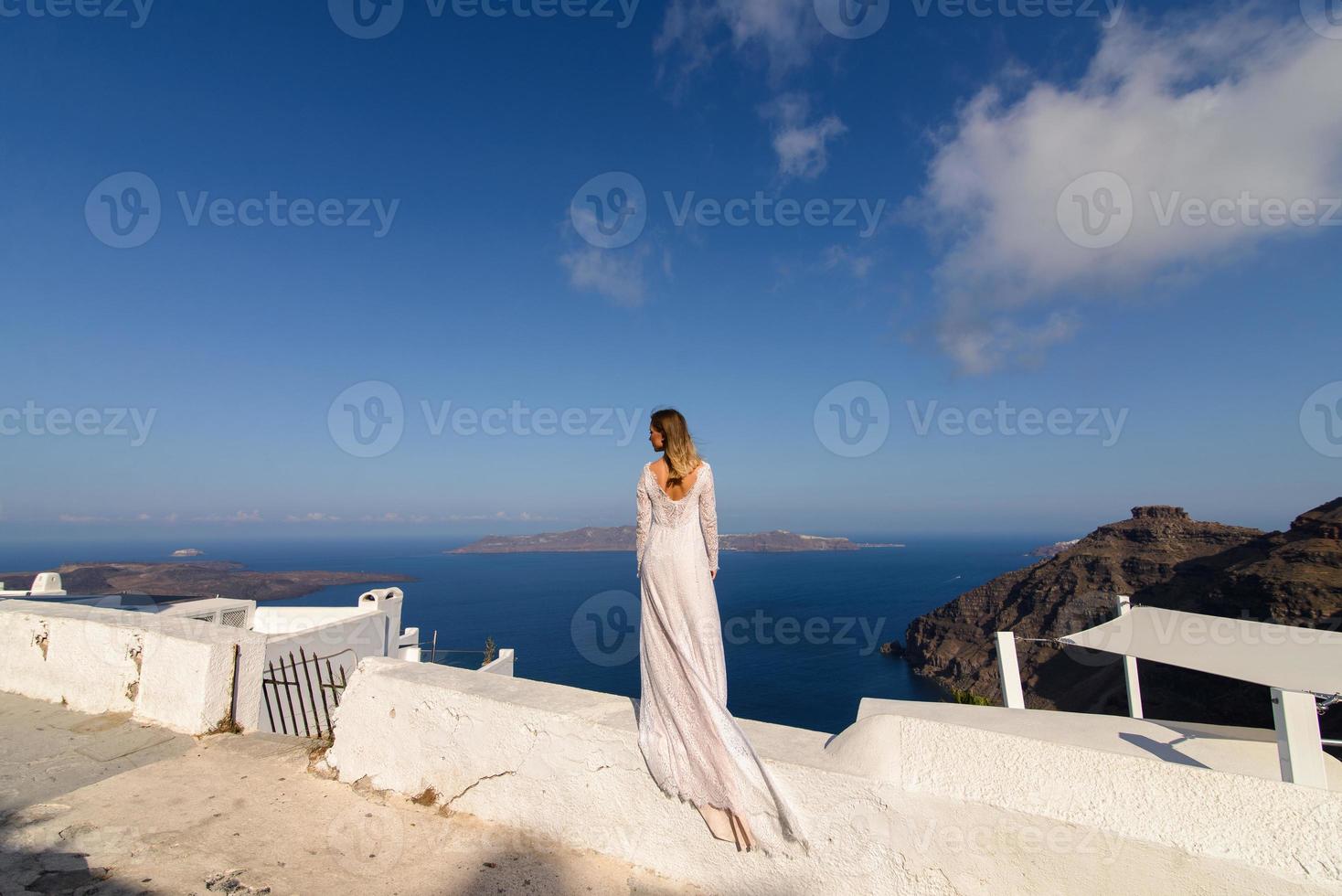 belle mariée en robe blanche posant sur le fond de la mer méditerranée à thira, santorin. photo