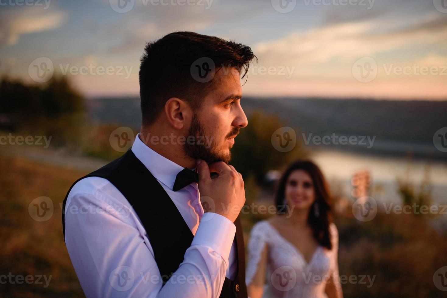 la mariée et le marié se promènent près du vieux château. le couple se tient dos à l'autre. photo