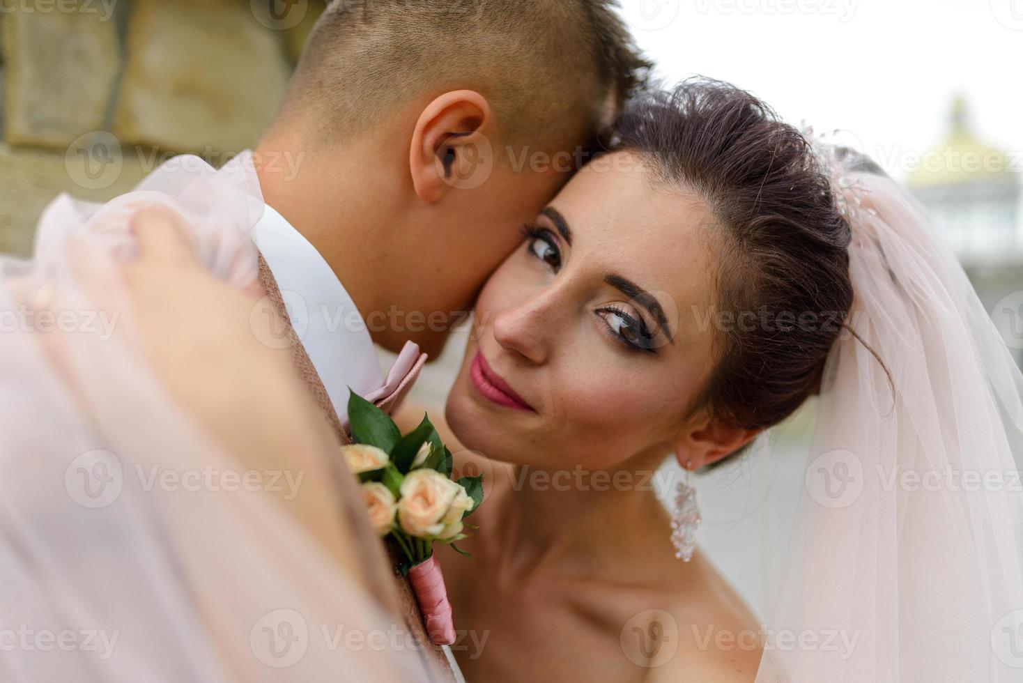 la mariée et le marié s'étreignent sous un voile et s'inclinent doucement la tête l'un vers l'autre. photo