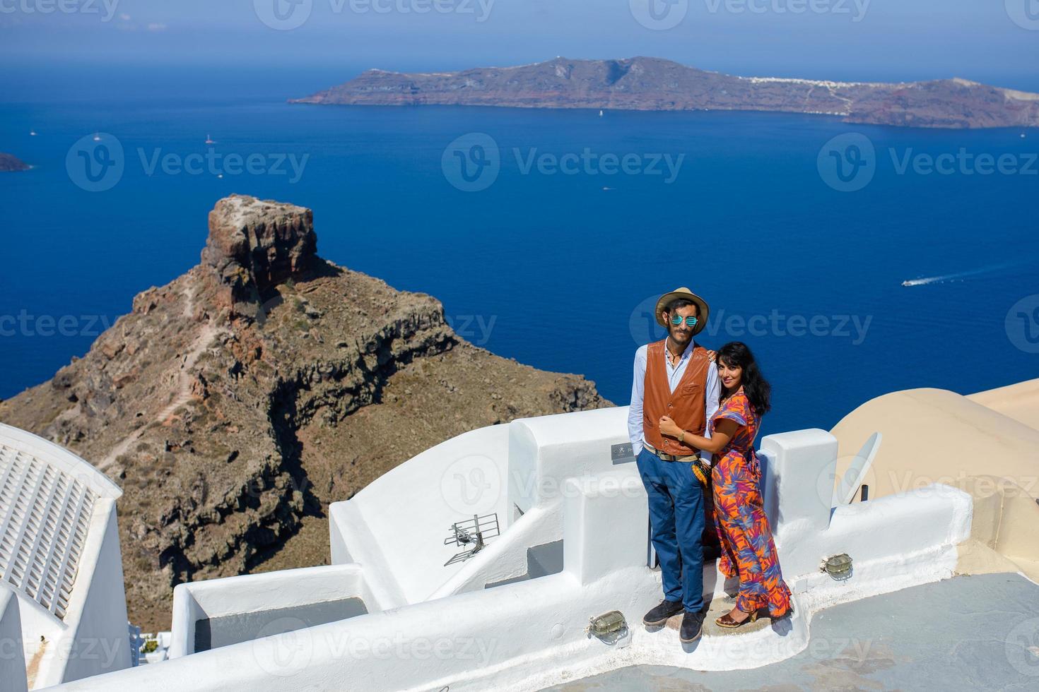 un homme et une femme se serrent dans leurs bras sur fond de rocher de skaros sur l'île de santorin. le village d'imerovigli. photo