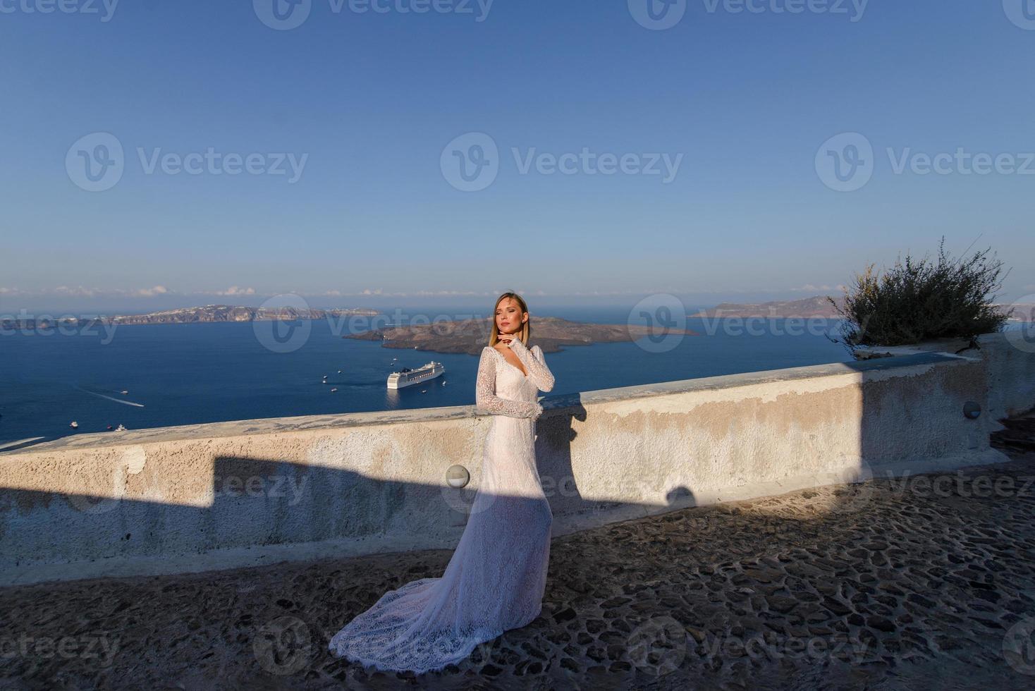 belle mariée en robe blanche posant sur le fond de la mer méditerranée à thira, santorin. photo