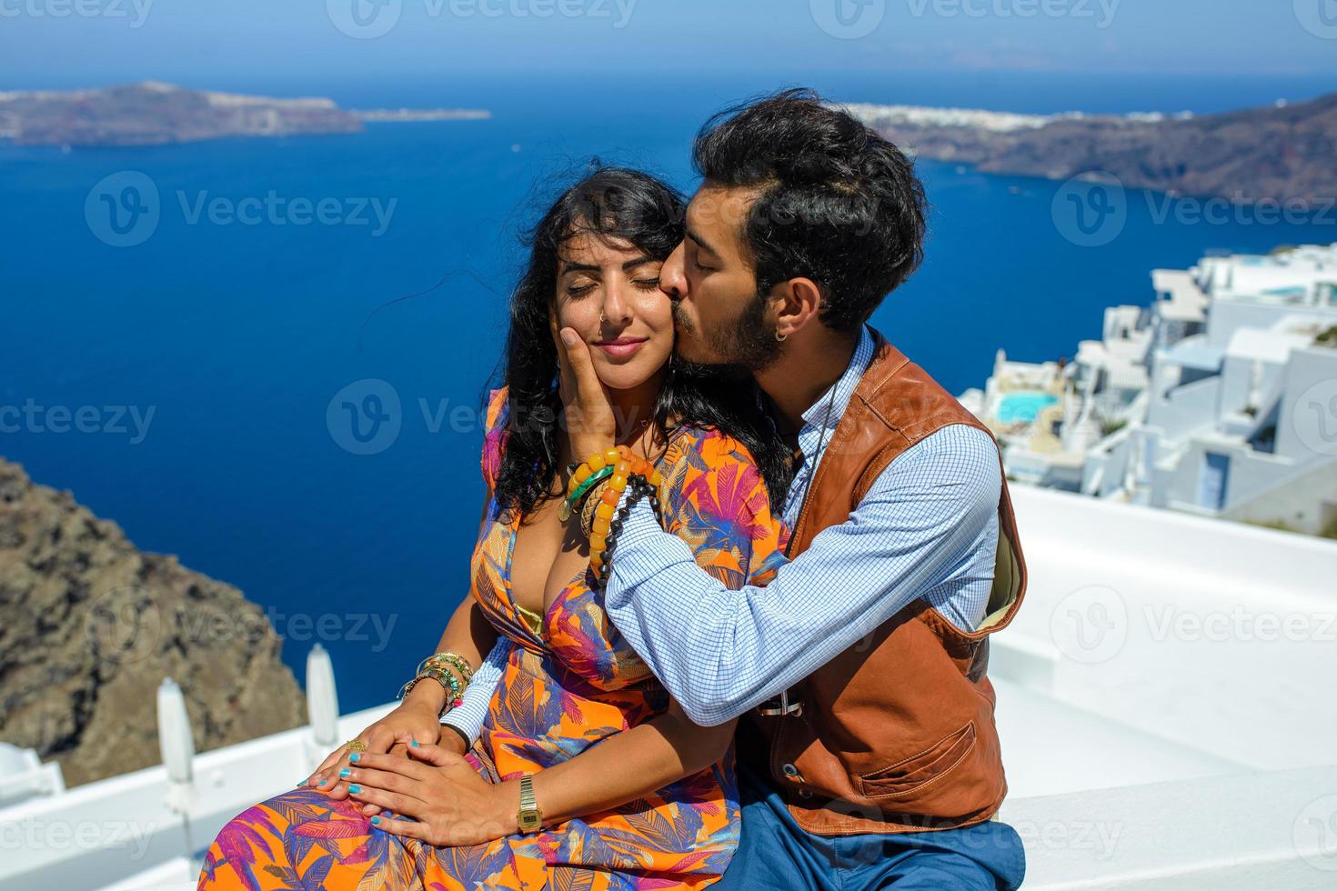 un homme et une femme se serrent dans leurs bras sur fond de rocher de skaros sur l'île de santorin. le village d'imerovigli. photo