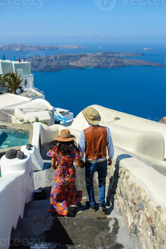 un homme et une femme se serrent dans leurs bras sur fond de rocher de skaros sur l'île de santorin. le village d'imerovigli. photo