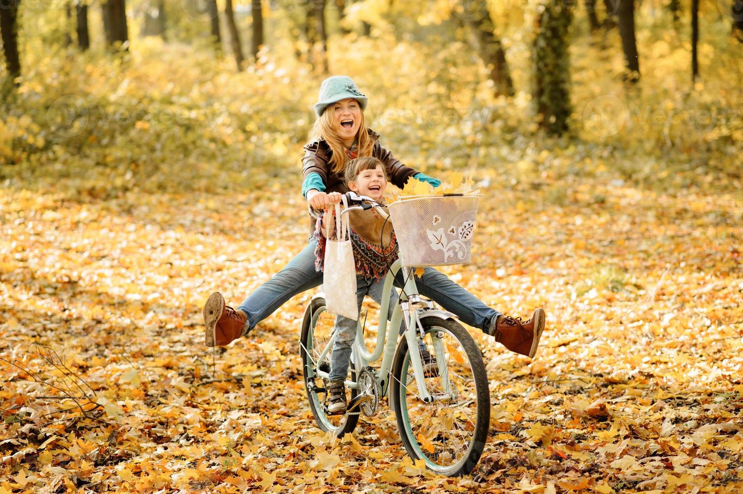 maman et fille s'amusent sur le même vélo. séance photo d'automne.