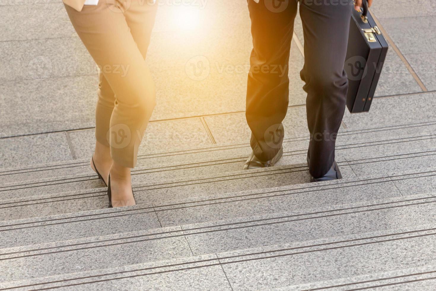 homme d'affaires et femme d'affaires qui monte les escaliers avec des sacs au bureau. photo