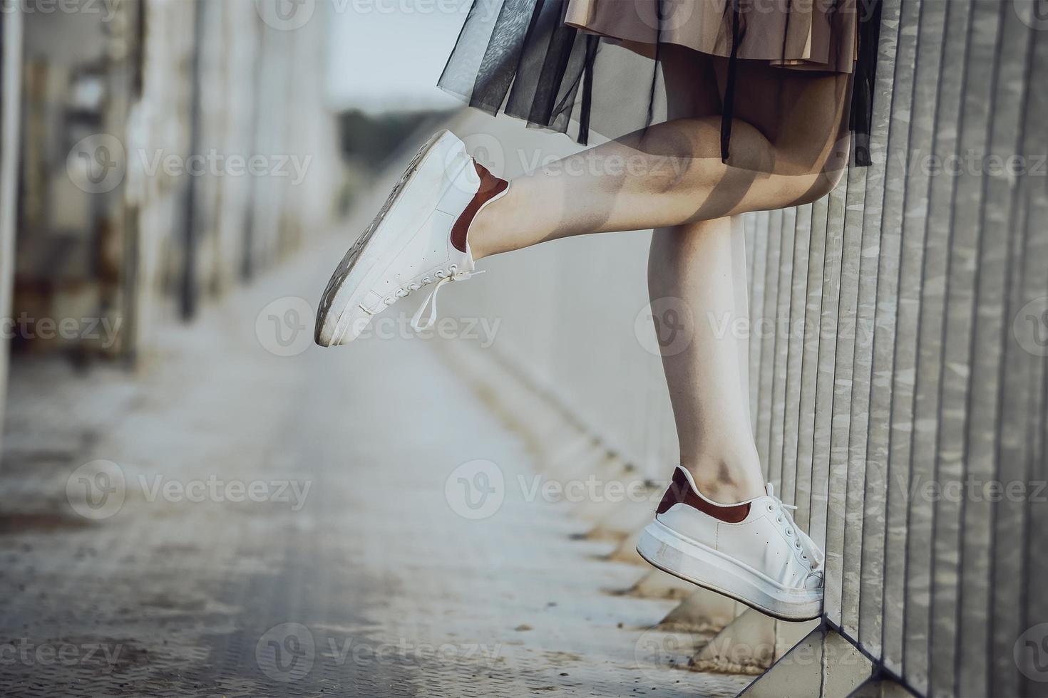 jambes adolescente en baskets blanches sur le pont. photo