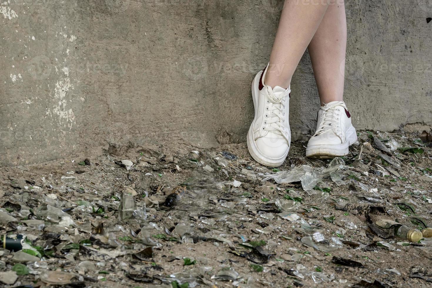 les pieds de l'adolescent dans un tas de verre brisé et de débris. adolescents en difficulté et toxicomanie photo