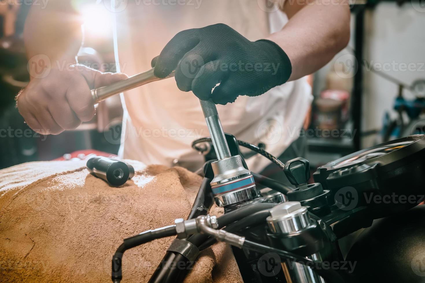 Mécanicien à l'aide d'une clé et d'une douille sur une moto dans un garage. photo