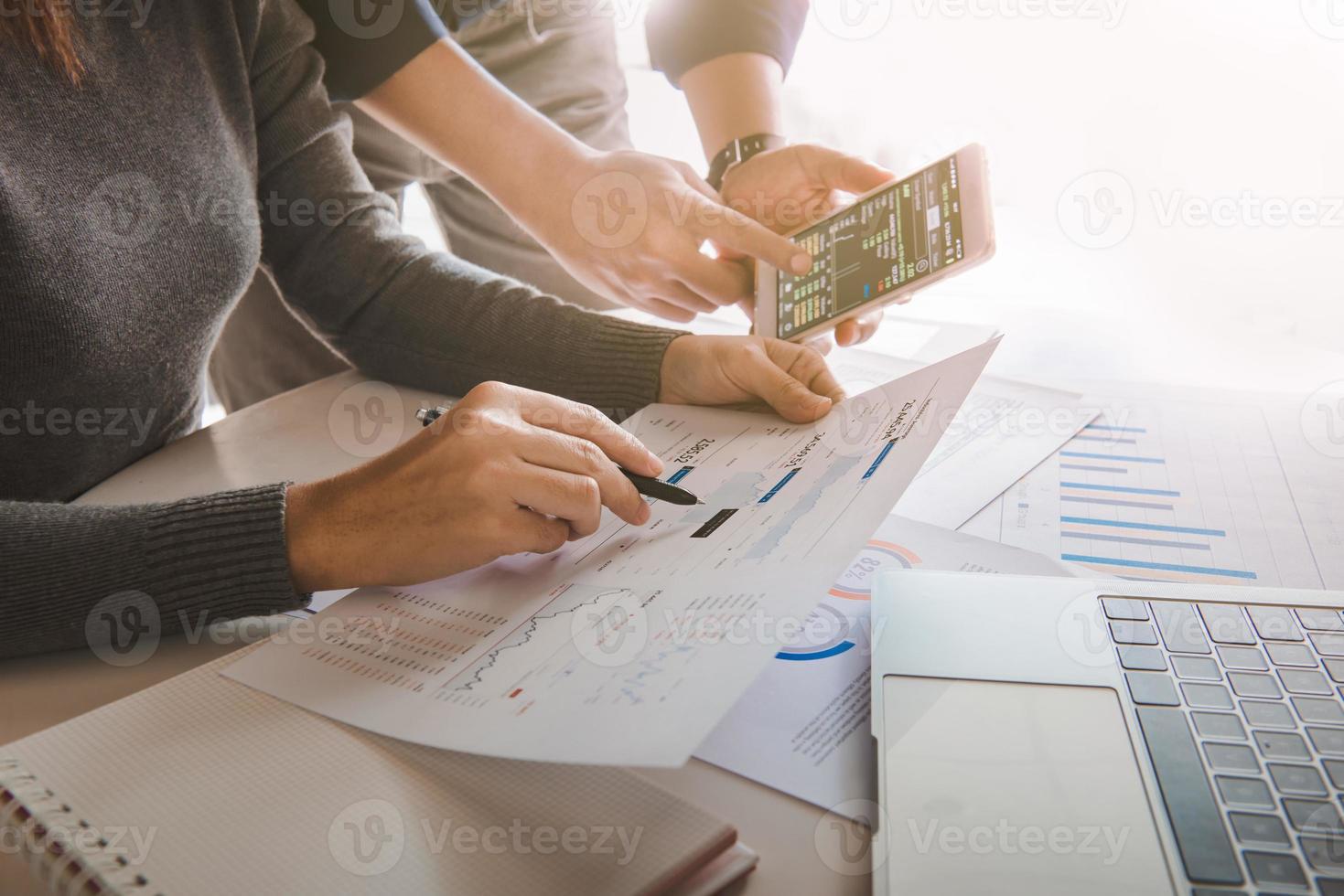 équipe commerciale analysant les données de vente et le graphique de croissance économique sur une table de bureau avec ordinateur portable et smartphone, remue-méninges, stratégie commerciale et planification. photo