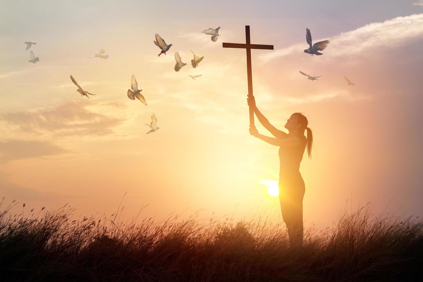 femme priant avec croix et oiseau volant sur fond de coucher de soleil nature, concept d'espoir photo