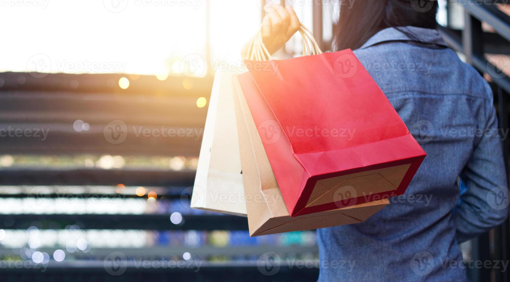 vue arrière de la femme tenant un sac à provisions en montant les escaliers à l'extérieur sur le fond du centre commercial photo