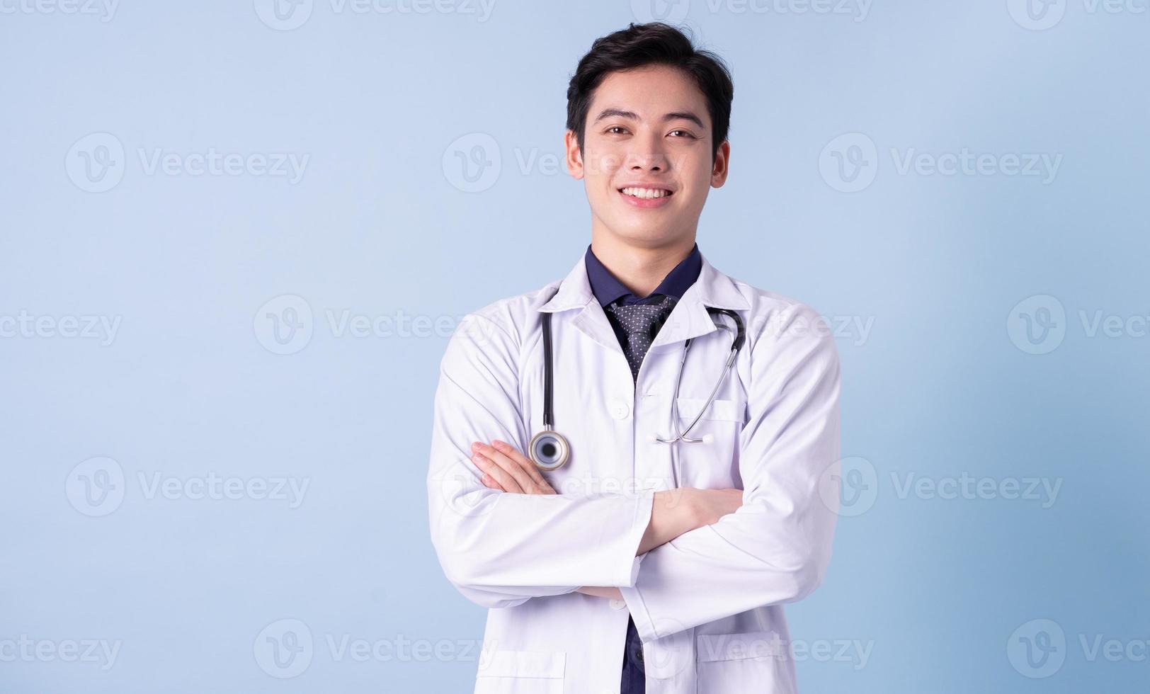 portrait de jeune médecin de sexe masculin asiatique sur fond bleu photo