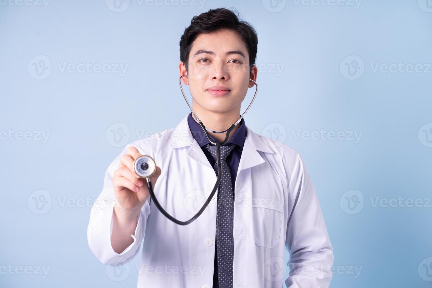 portrait de jeune médecin de sexe masculin asiatique sur fond bleu photo