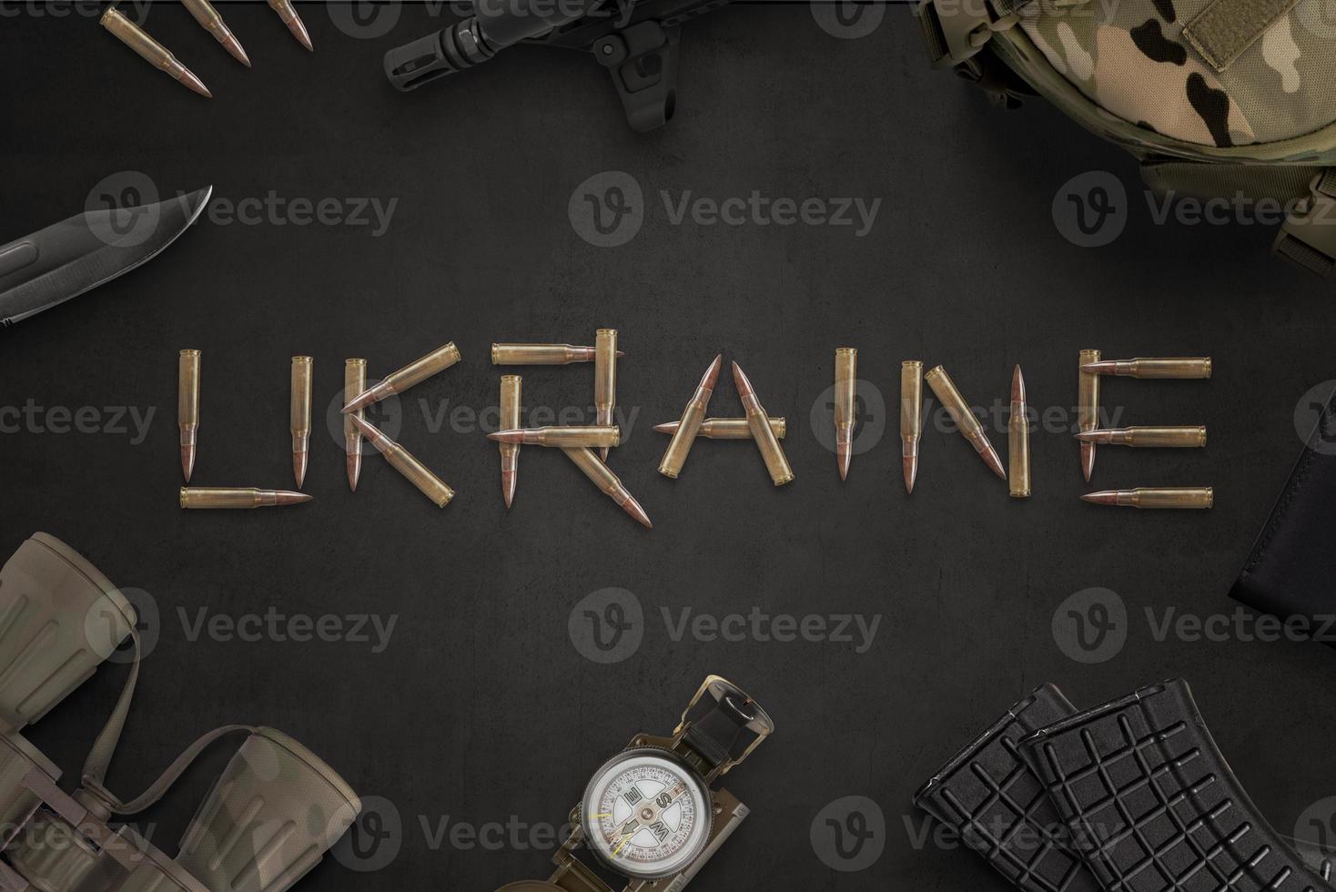 concept de guerre en ukraine. texte ukrainien écrit avec des balles d'un fusil automatique et entouré d'équipements militaires photo