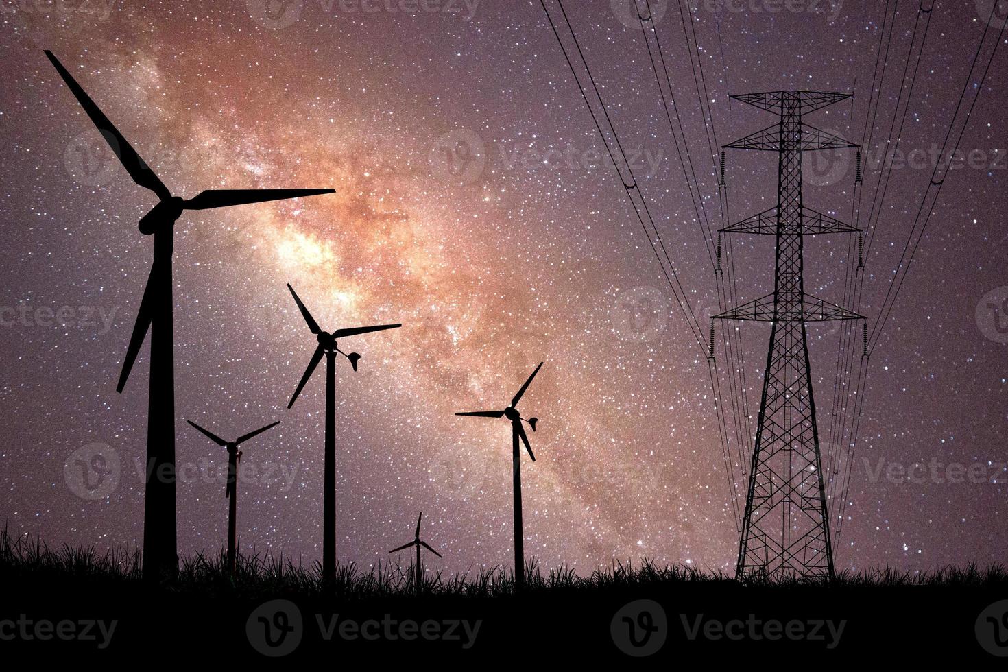 une silhouette d'un moulin à vent utilisé pour produire de l'électricité dans un champ sur un magnifique fond de voie lactée. photo