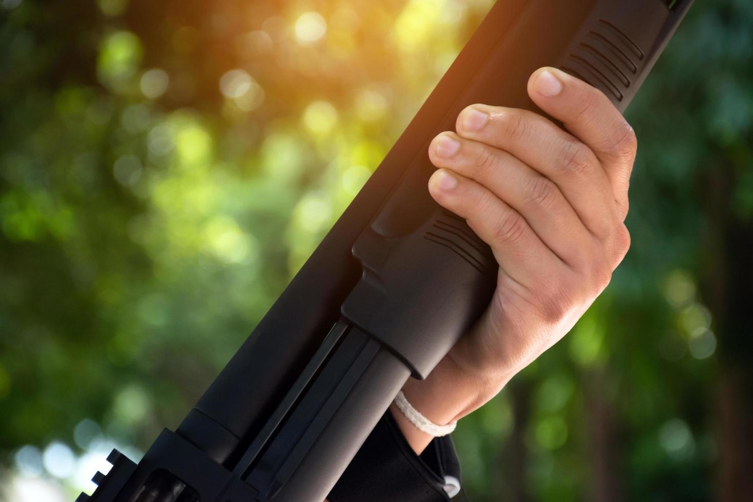 un jeune garçon asiatique tient un fusil de chasse dans les mains, une mise au point douce et sélective sur les mains. photo