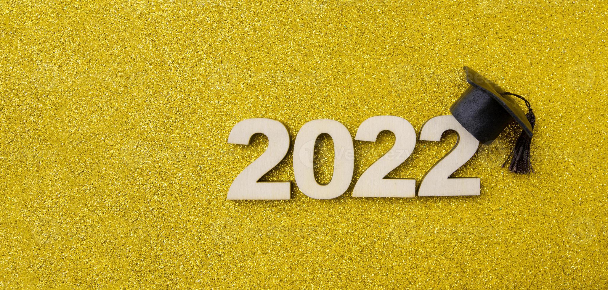 chapeau ou casquette gradué avec numéro en bois 2022 sur fond jaune scintillant. format de bannière de concept de classe 2022 photo