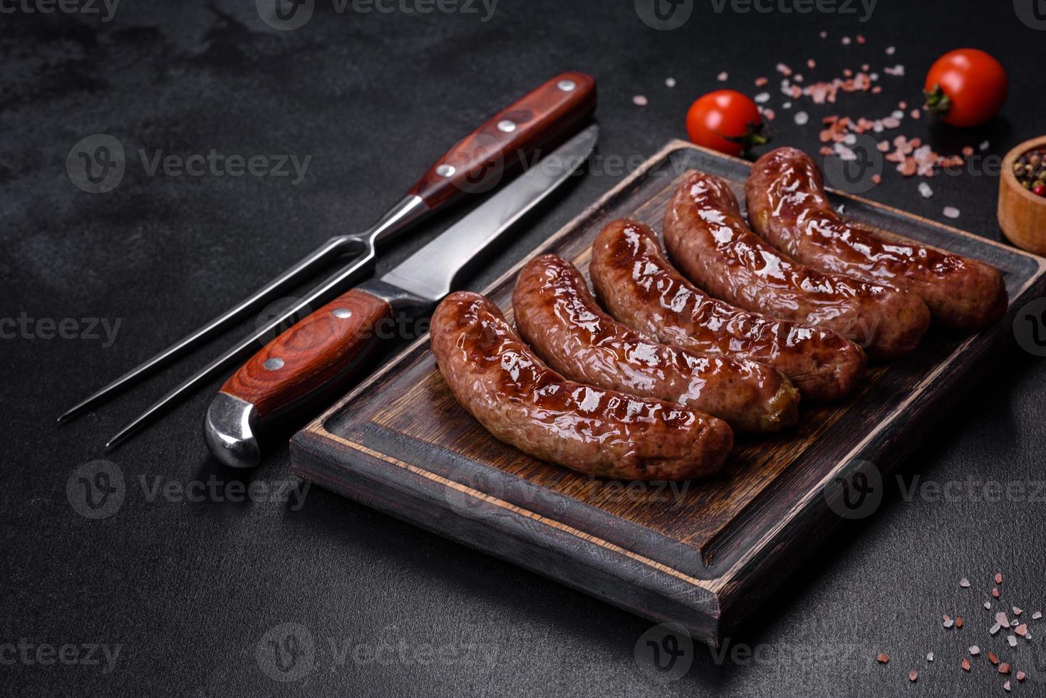 saucisses grillées avec des ingrédients sur une planche à découper sur un fond de pierre photo