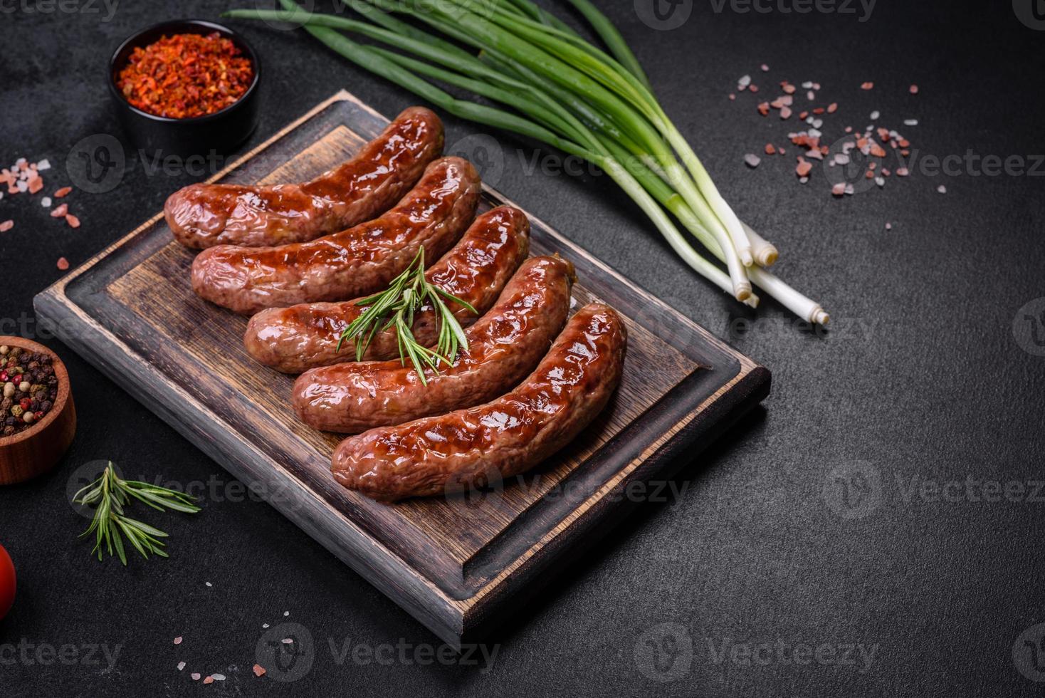 saucisses grillées avec des ingrédients sur une planche à découper sur un fond de pierre photo