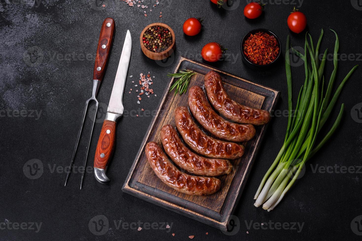 saucisses grillées avec des ingrédients sur une planche à découper sur un fond de pierre photo