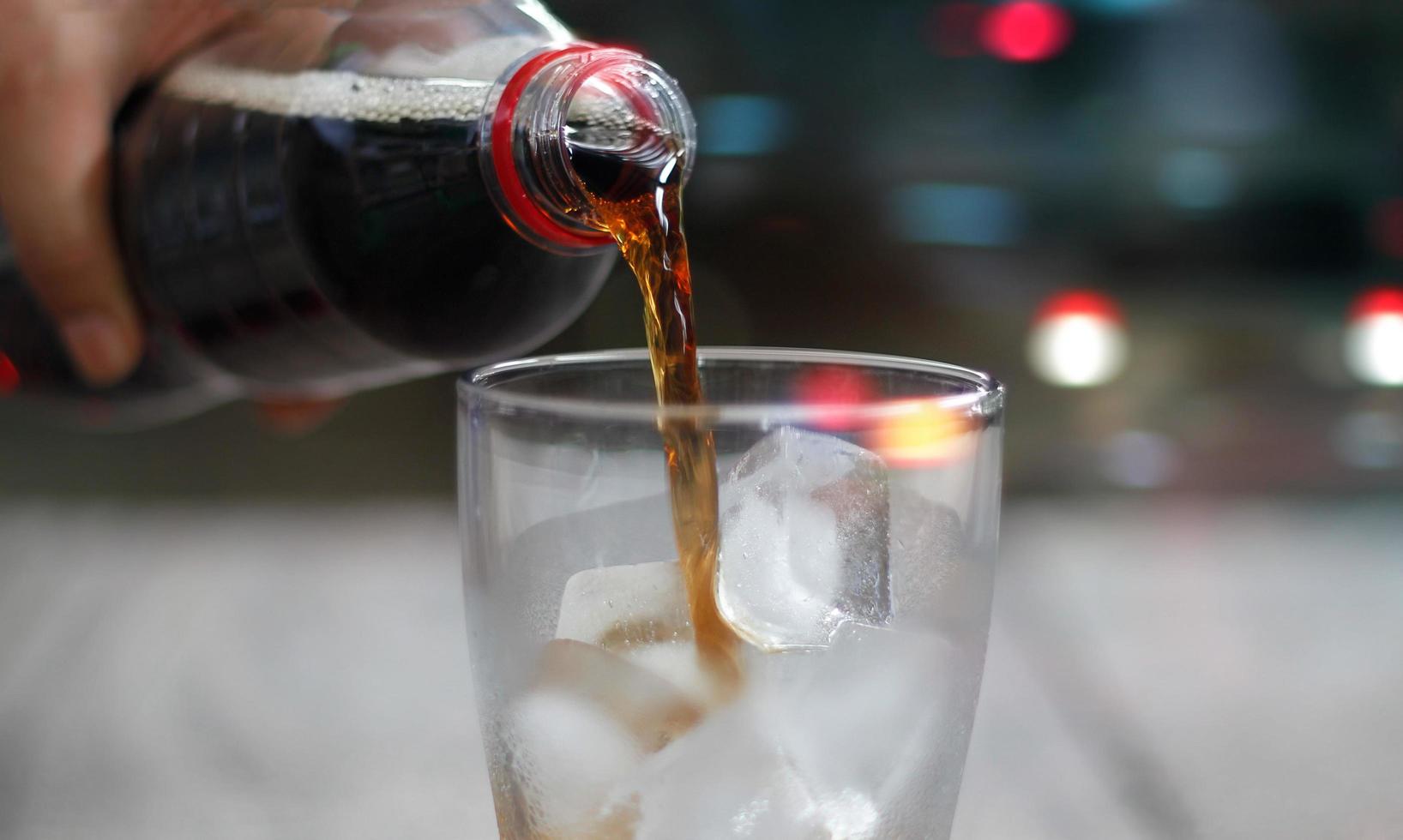 vue de face, verser du soda au cola avec de la glace et des bulles, boisson froide sur fond de nuit photo